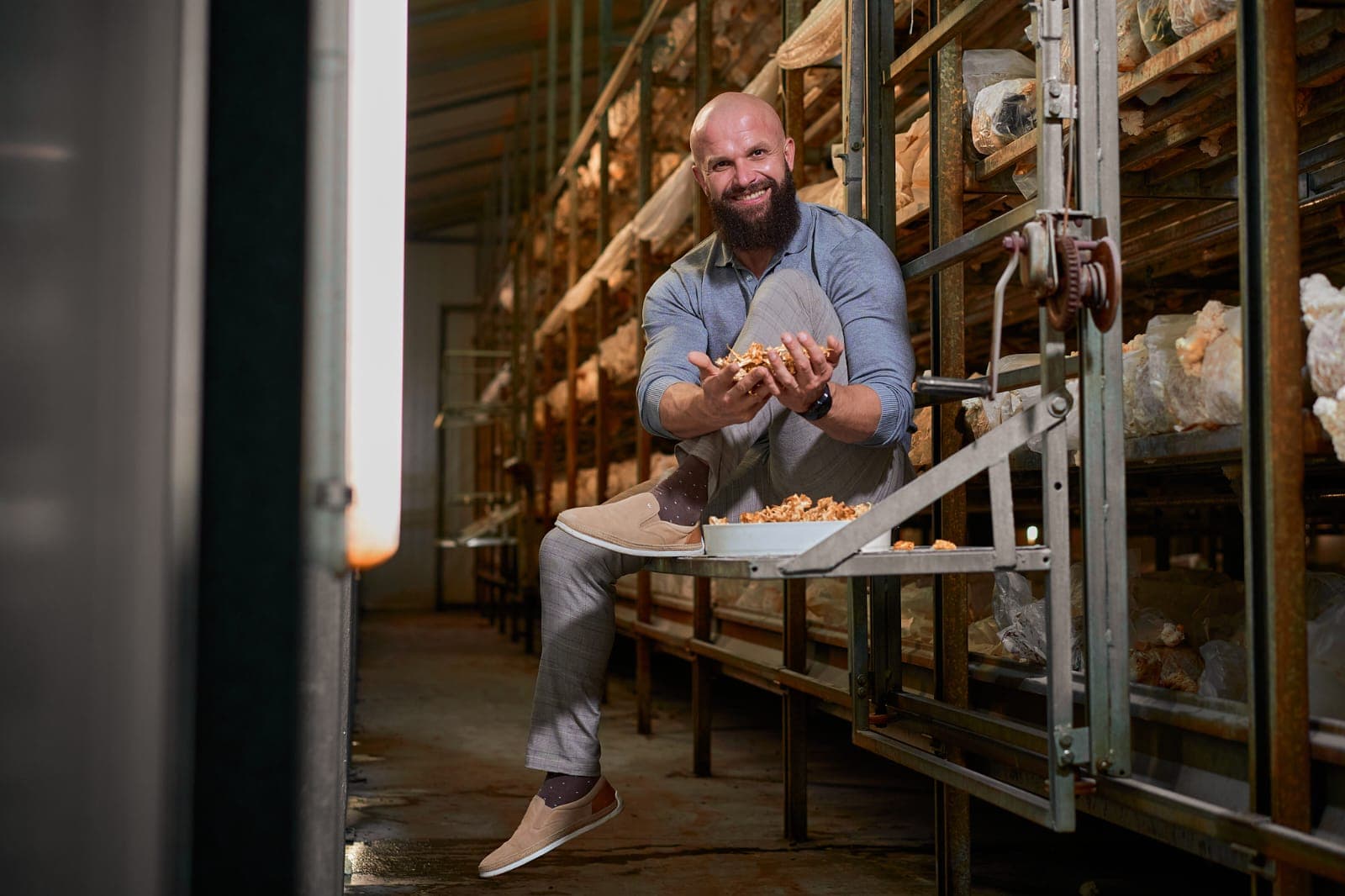 Cezary Szewczuk, COO of Mushroom Empire, in the industrial-scale mushroom cultivation hall with multi-tier shelves — Lublin region, Poland.